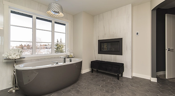 Modern bathroom with freestanding bathtub, large window, and decorative fireplace.
