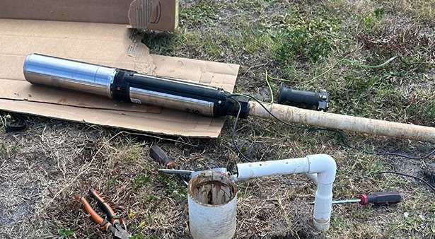 Plumbing tools and pipes on grass during outdoor repair.