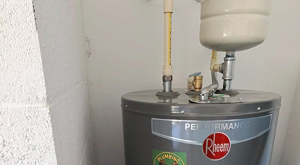 Water heater with pipes and valves in a utility room.