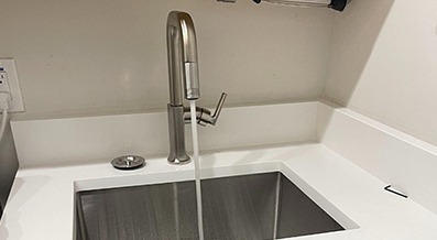 Water running from a stainless steel faucet into a kitchen sink.