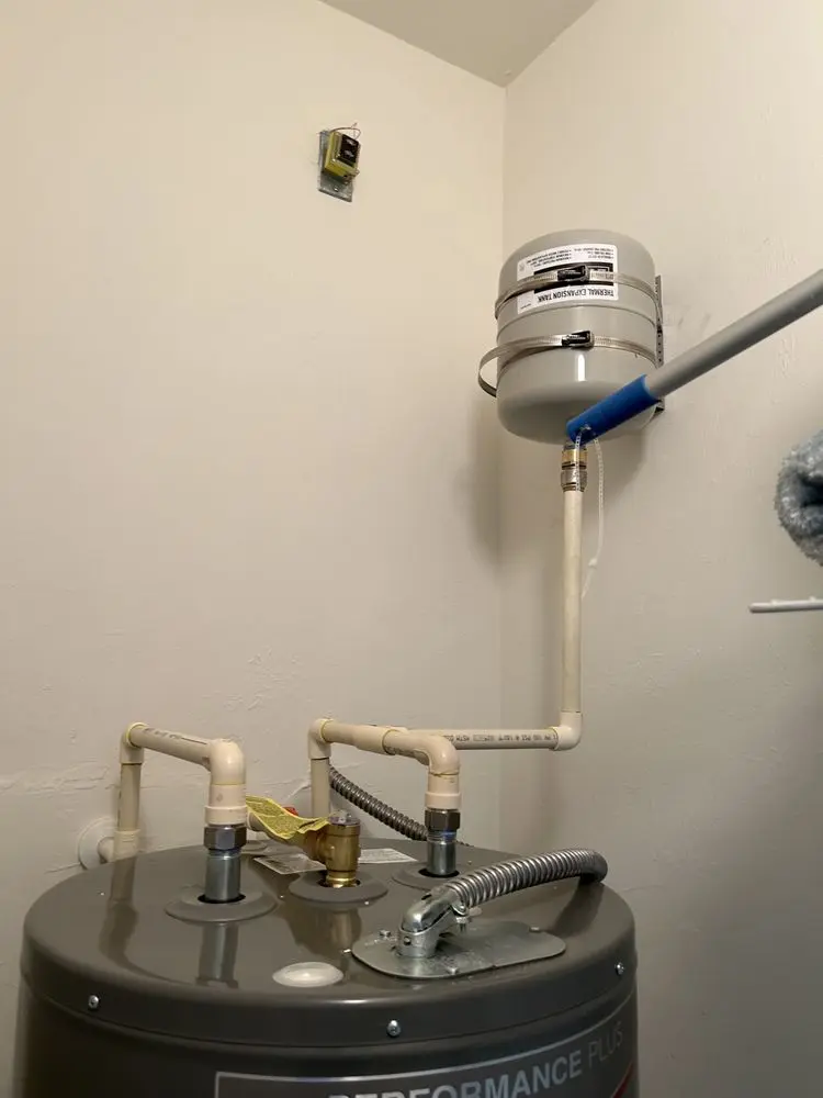 Water heater with connected piping system in a utility room.