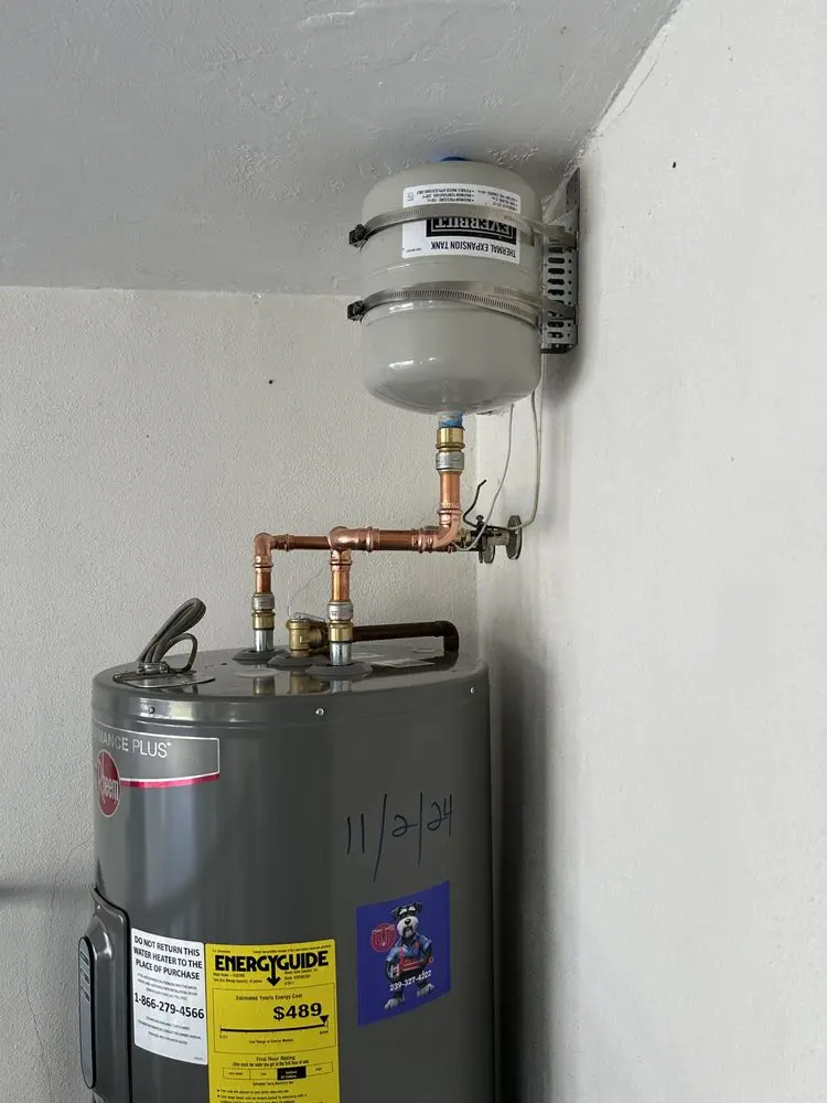 Water heater with expansion tank and copper piping on a white wall.