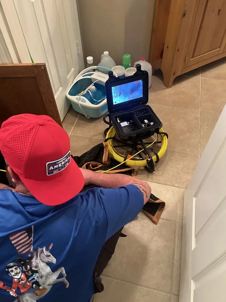Plumber inspecting through a camera on a yellow cable reel.