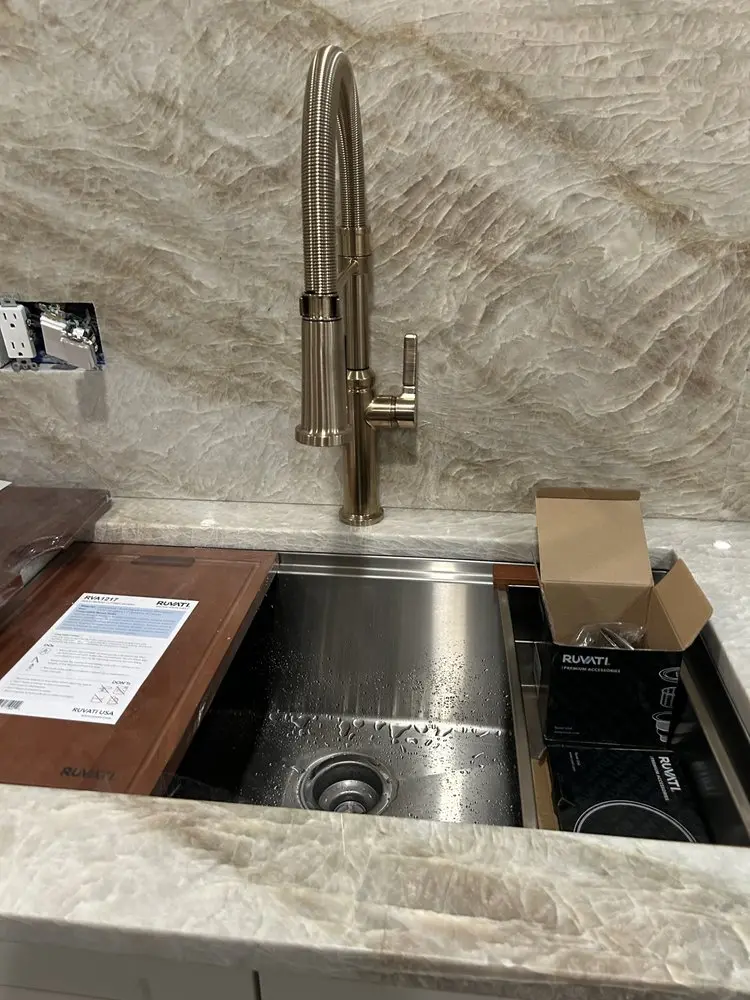 Modern kitchen sink with silver faucet and a marble counter.