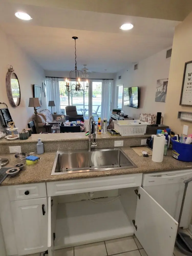 Modern kitchen interior with sink, countertop, and open cabinets in apartment.