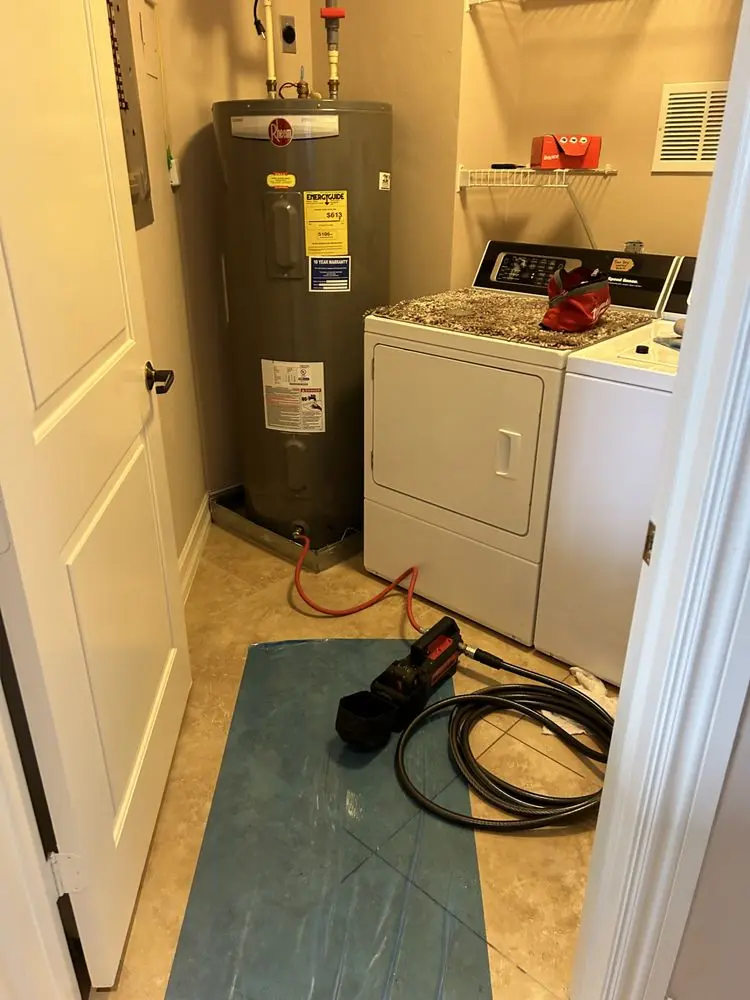 Laundry room with water heater, washer, dryer, and plumbing tools on the floor.