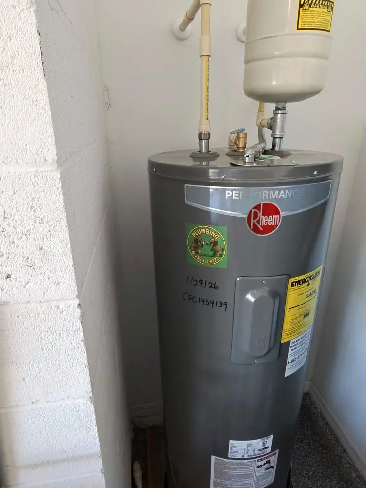 Water heater installed in a utility room with labeling and yellow pipes.