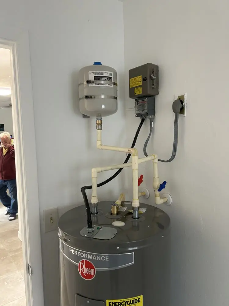 Water heater installation with connected pipes and electrical box on wall.