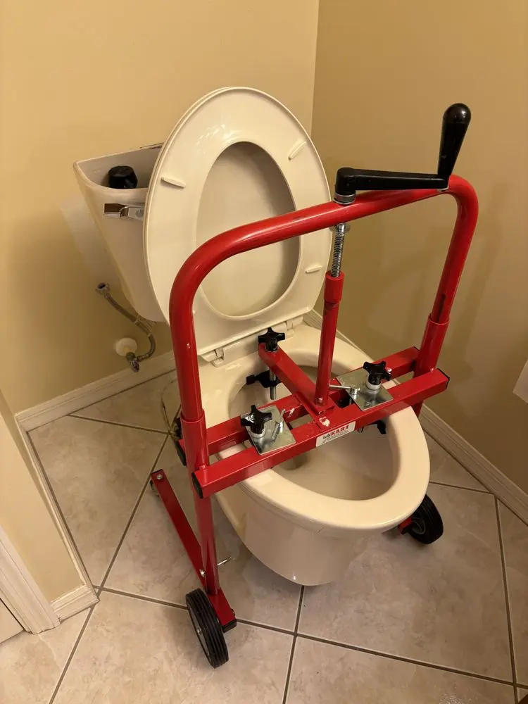 Toilet repair tool positioned above a toilet bowl in a bathroom.